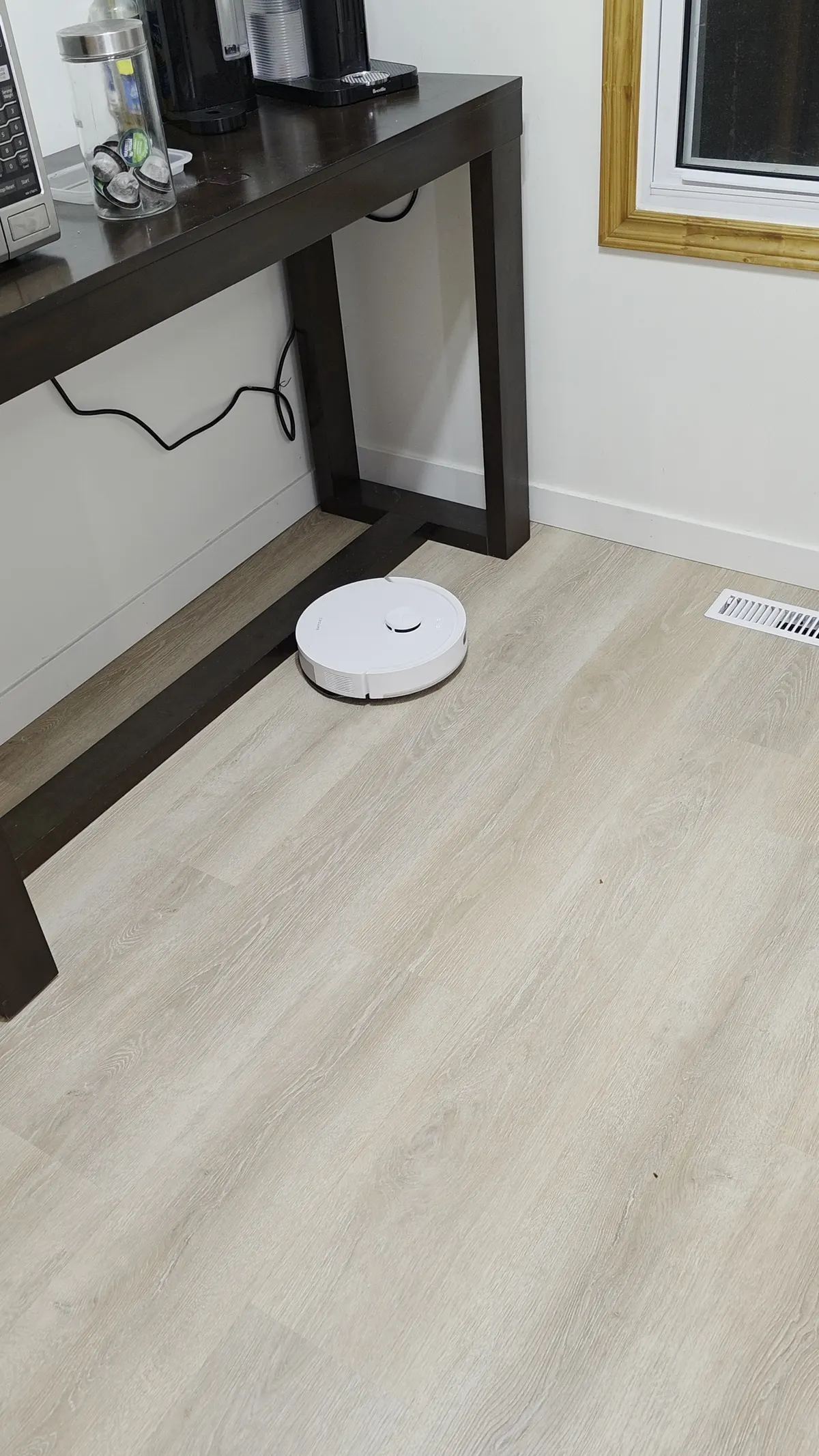 Dreame D20 Air Plus robot vacuum crossing a light vinyl plank floor near a desk