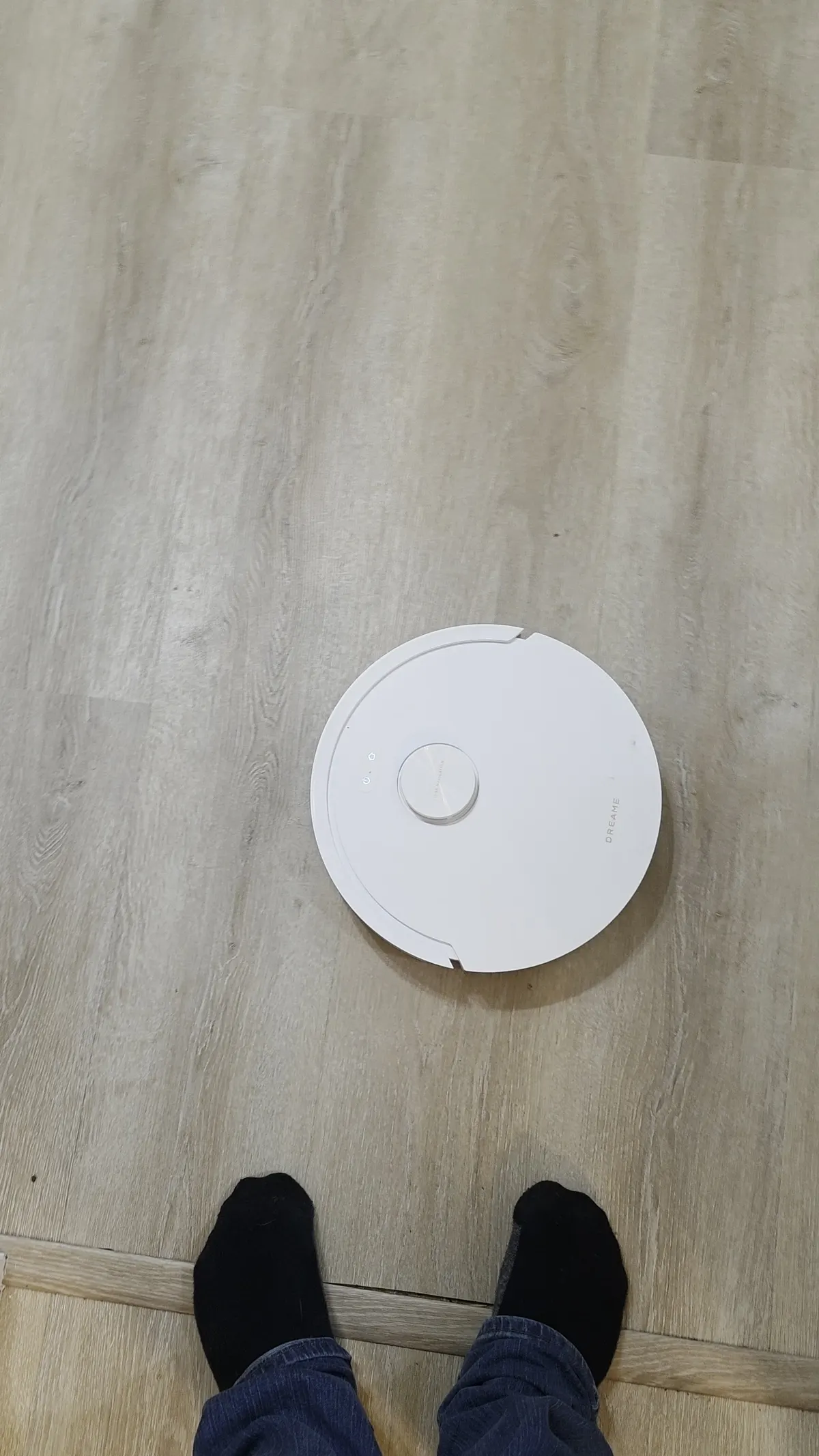 Top-down view of the Dreame D20 Air Plus near a doorway threshold on vinyl flooring