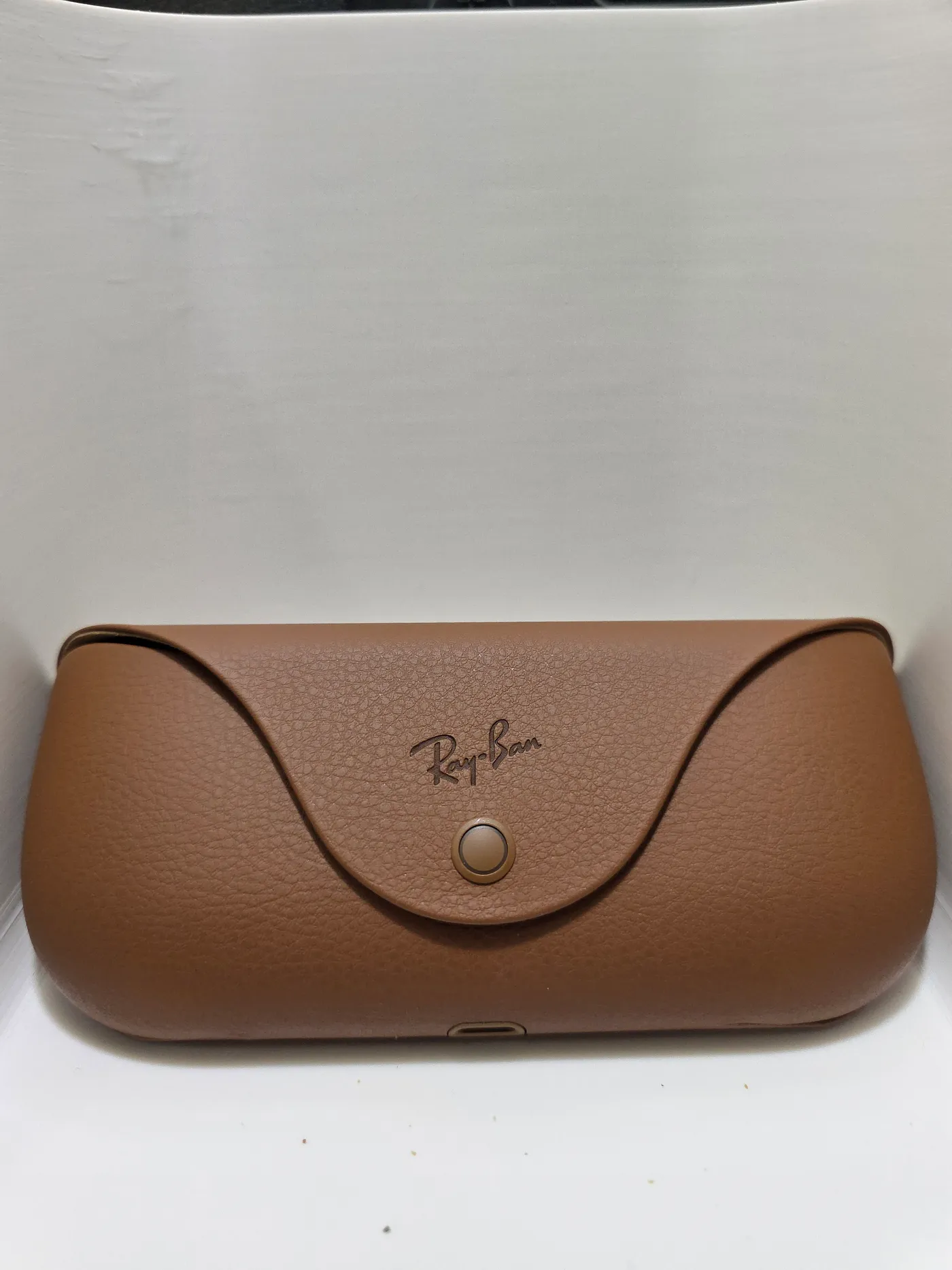 Brown Ray-Ban Meta charging case with snap closure and charging port
