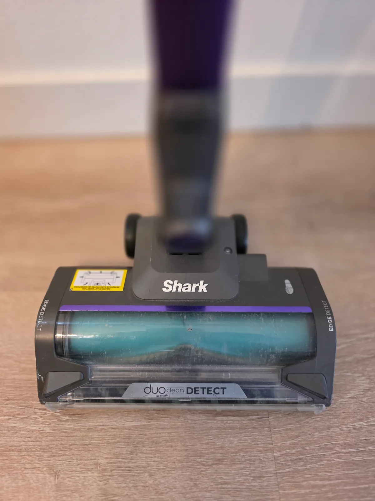 Close-up of the Shark DuoClean Detect floor head with a teal soft roller on a vinyl floor