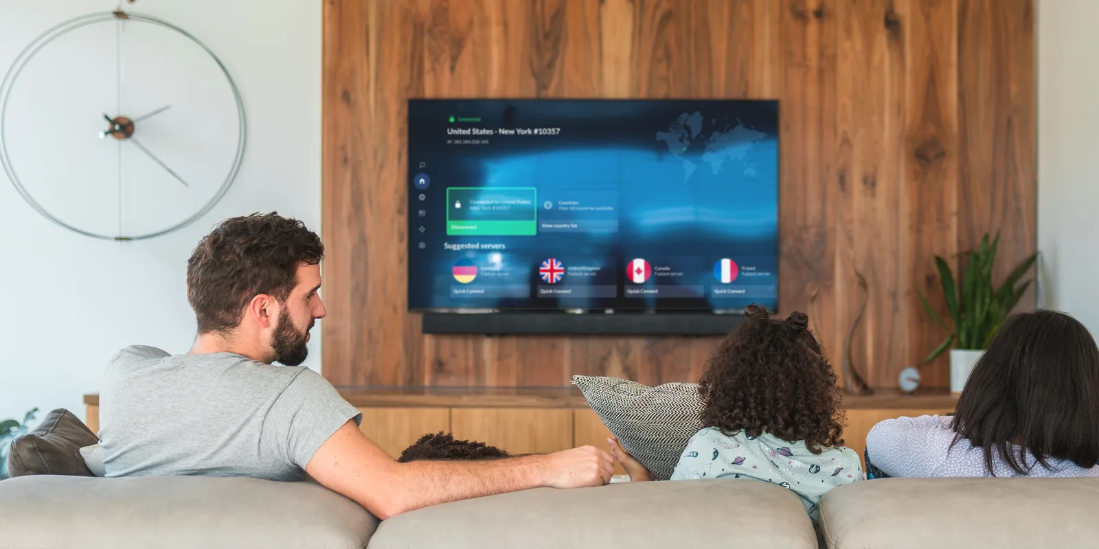 A family on a couch watching a TV that shows the NordVPN app connected to a server